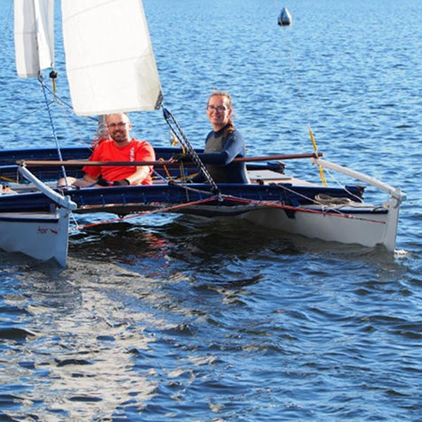 Small catamaran on the water crewed by two