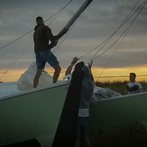 A man lifting the mast on a catamaran