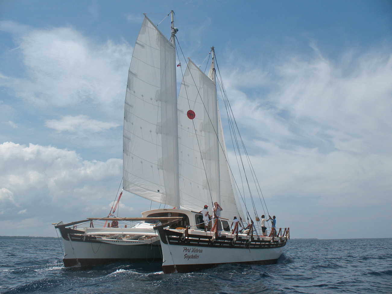 Rear view of Islander 65, wind in the sails, blue and cloudy sky