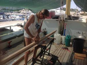 Hanneke sanding a piece of wood on deck