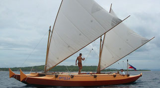 Tama Moana with sails up, people aboard