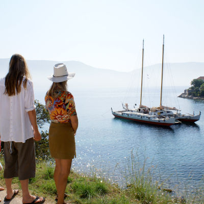 Two people looking out into a bay with a large catamaran at anchor