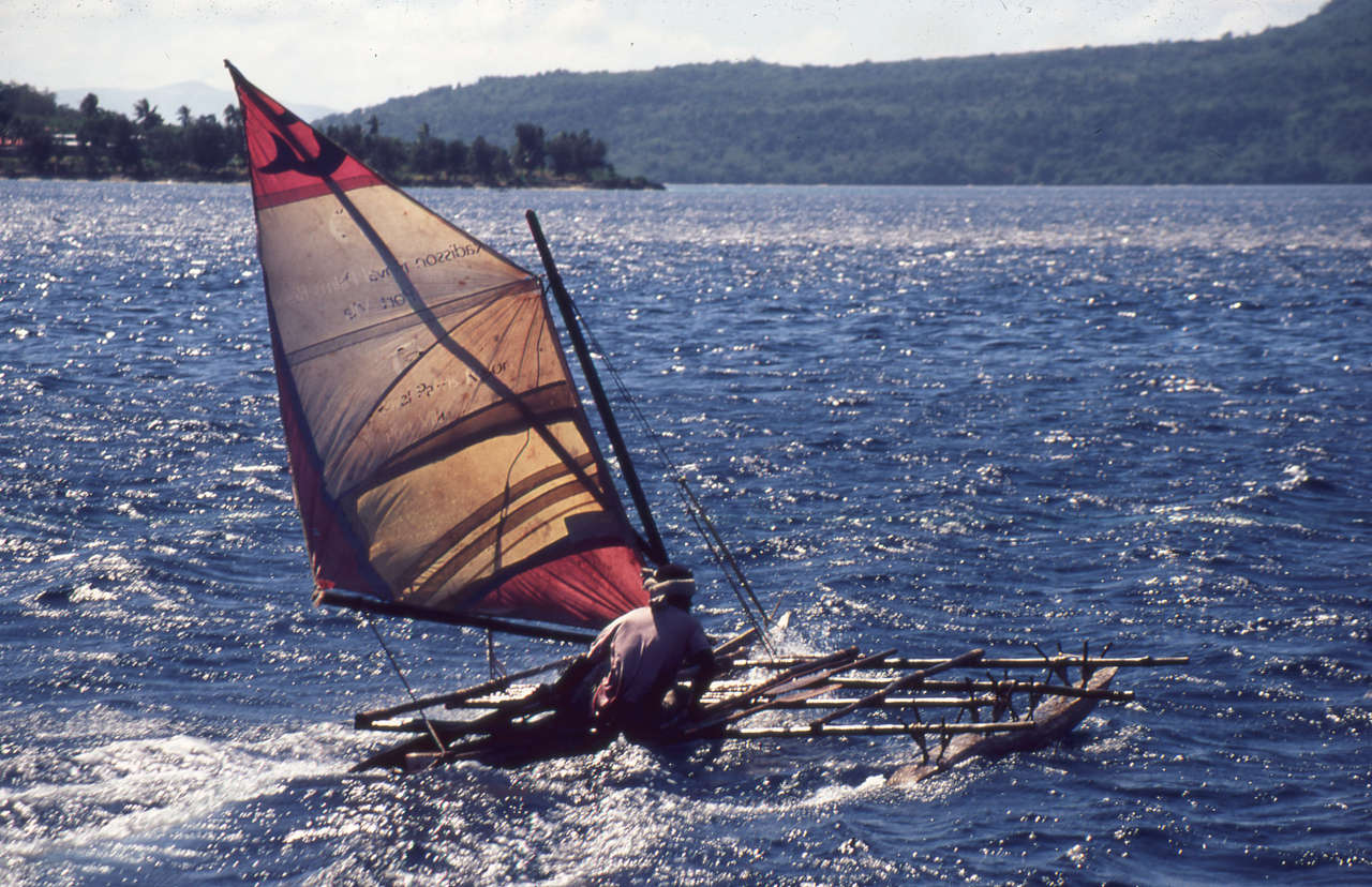 Outrigger canoe sailing on a sparkling sea