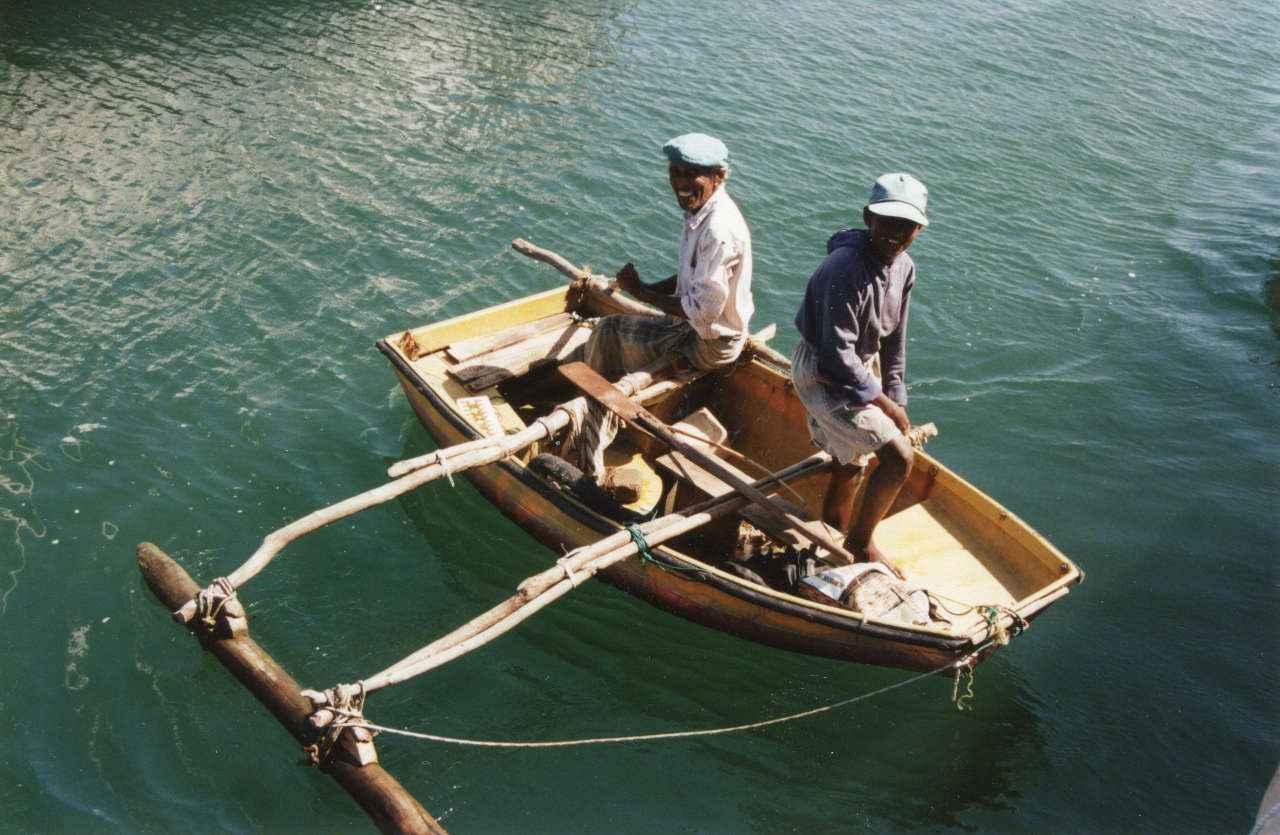 Dinghy with outrigger on the water, two people aboard
