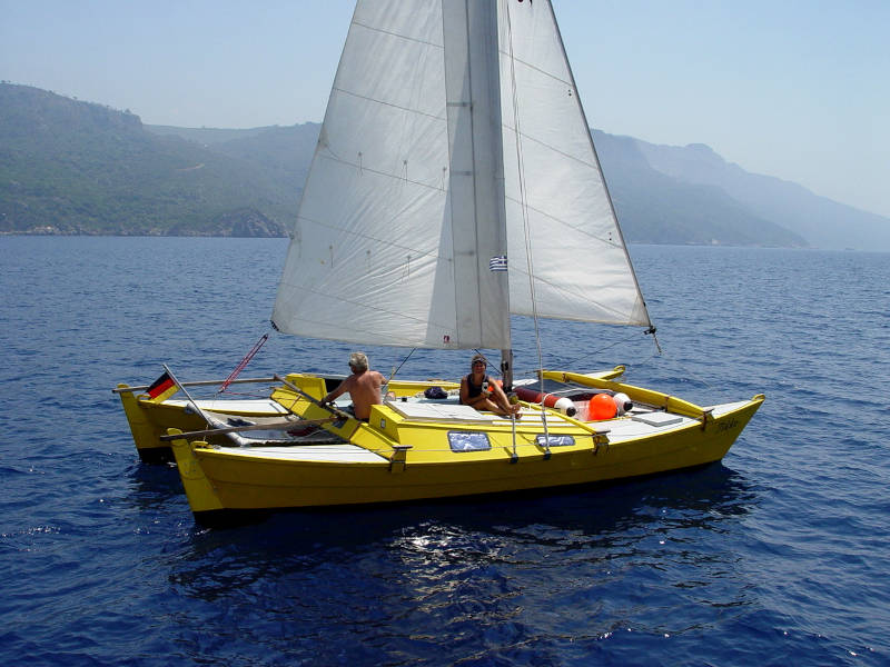A yellow catamaran sailing in bright sunshine