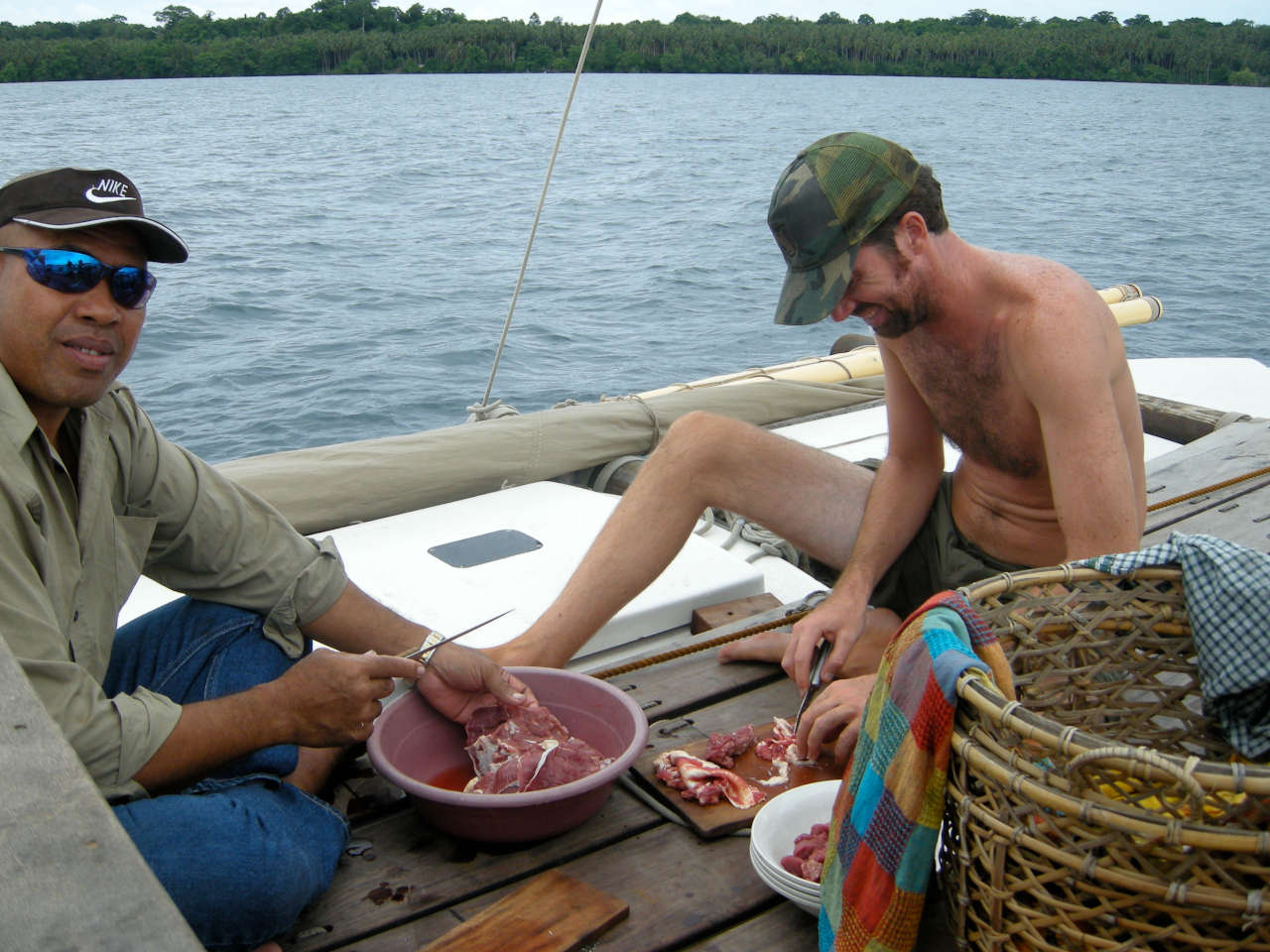 Two people chopping meat into a bowl on deck