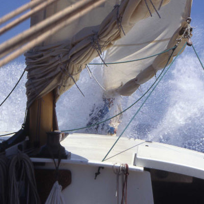 Two reefed sails, seawater spraying everywhere