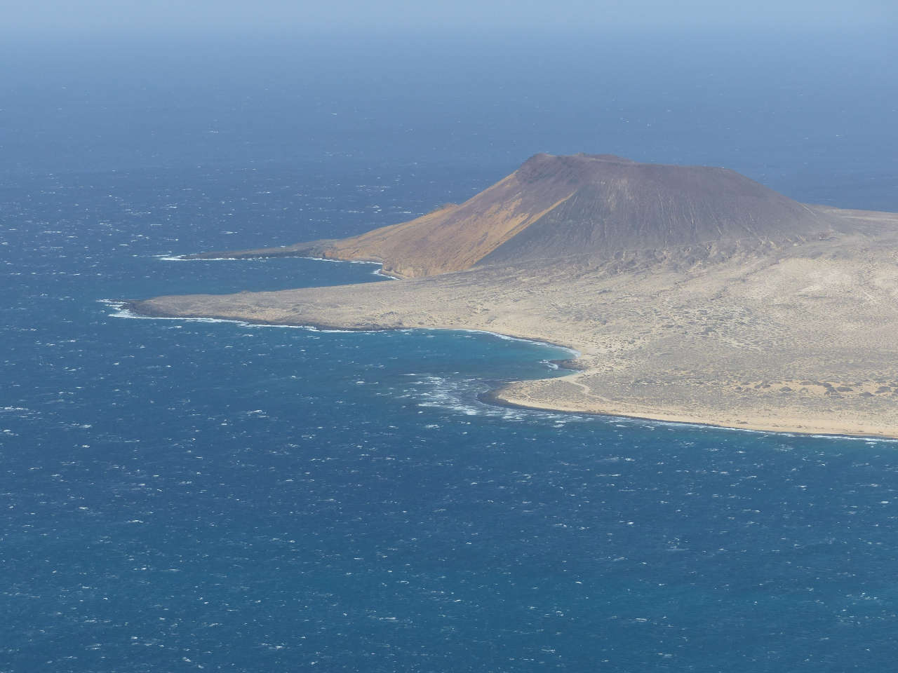 An island viewed from a great height, white caps on the waves