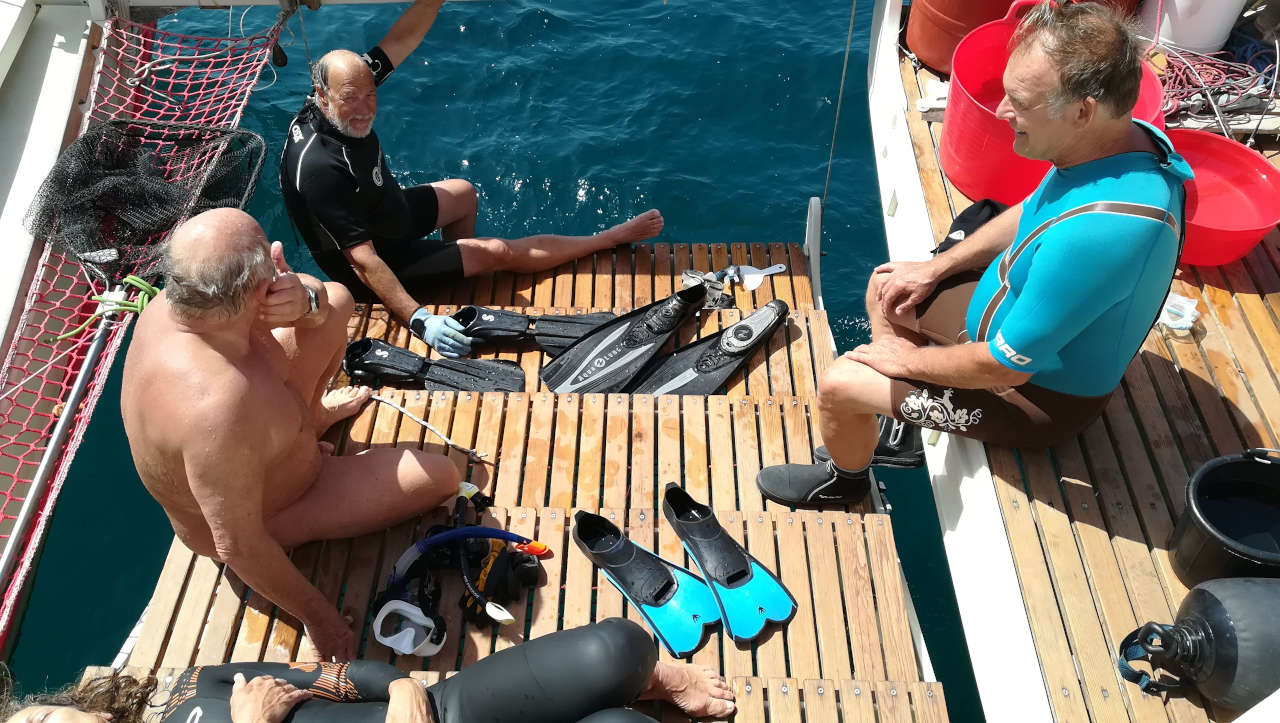 Three men on the stern ramp with snorkelling gear