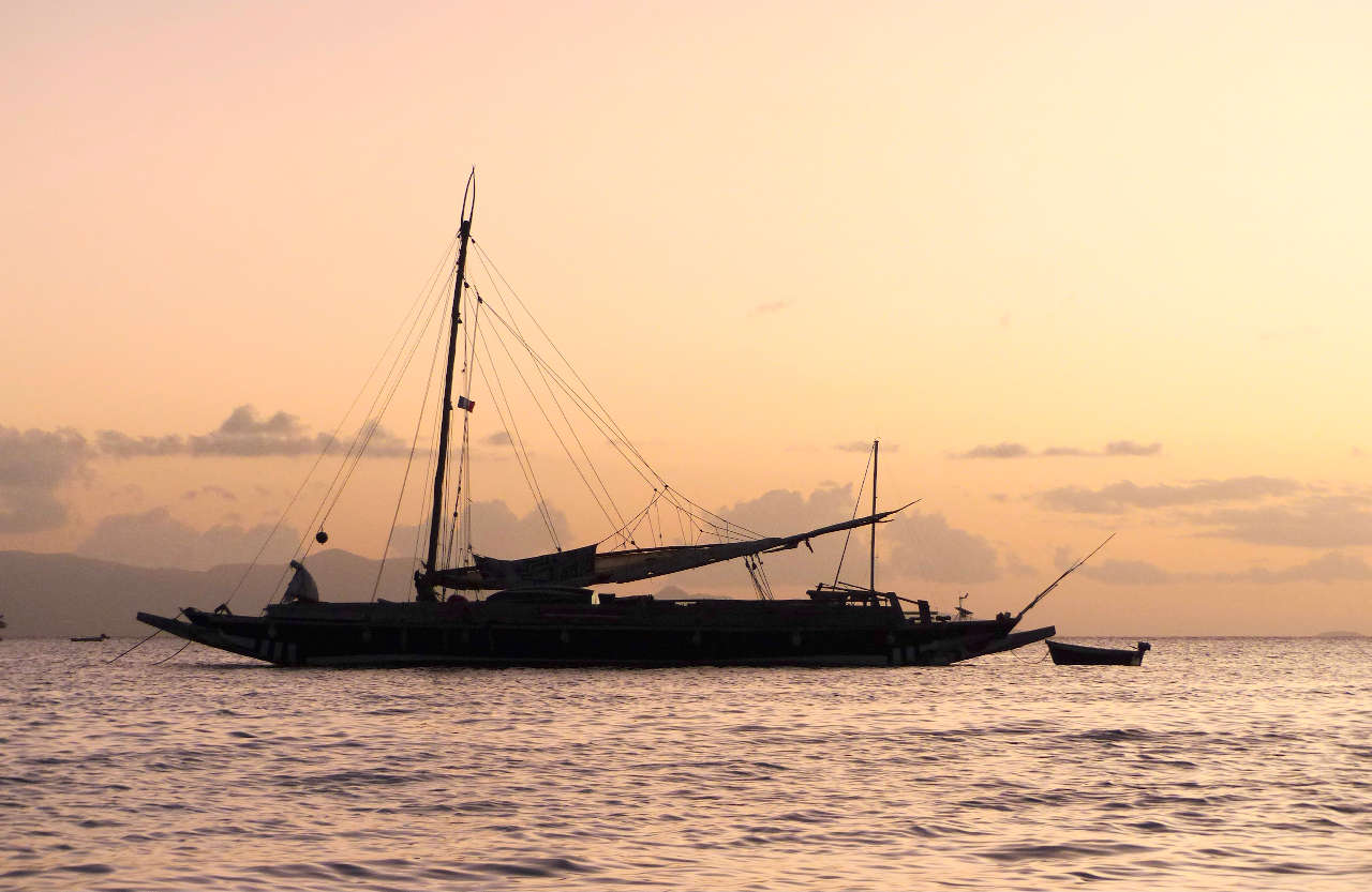 Sailing double canoe against a sunset