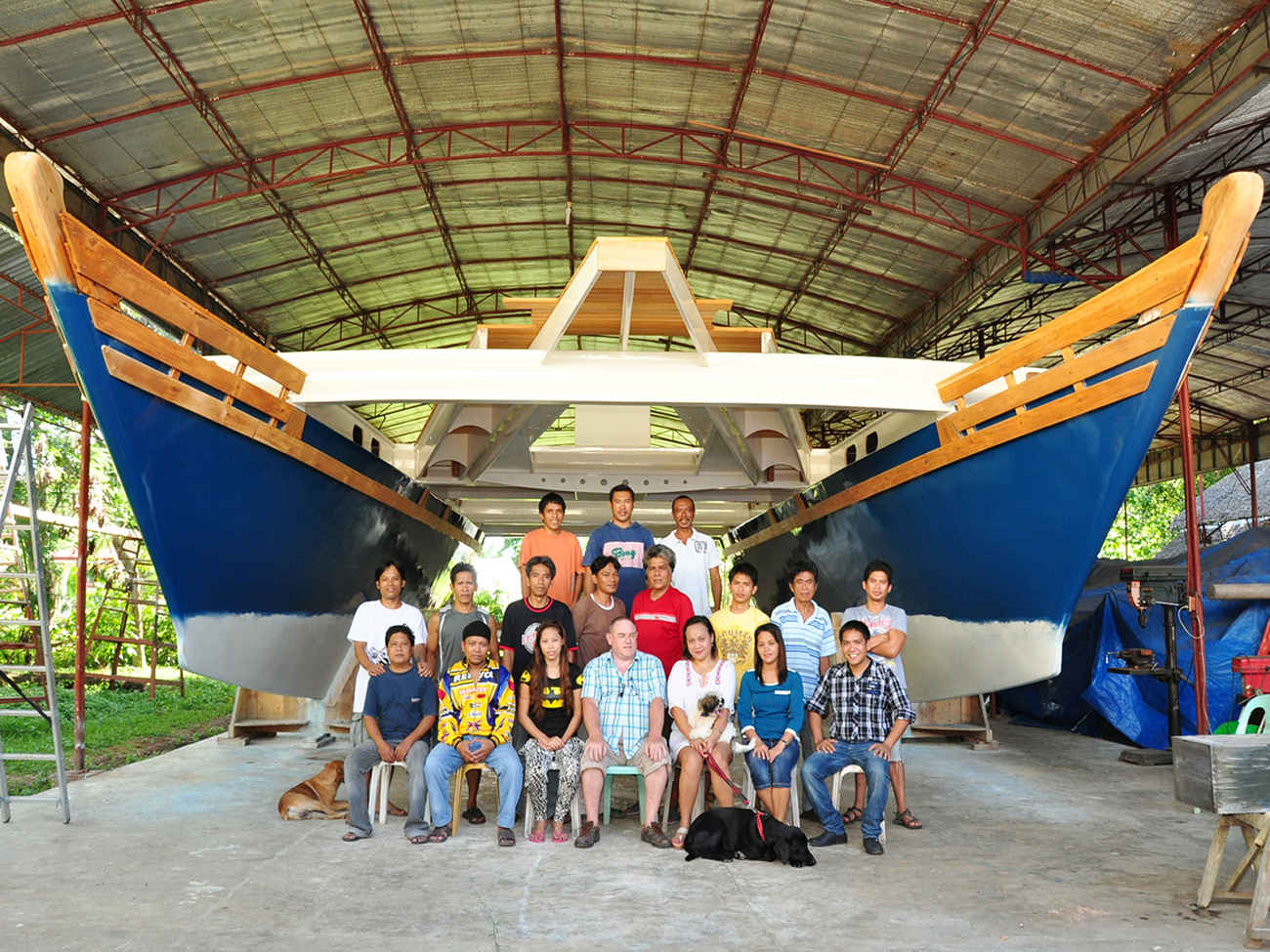 The Andy Smith Boatworks crew, posing for a photo under two large catamaran hulls