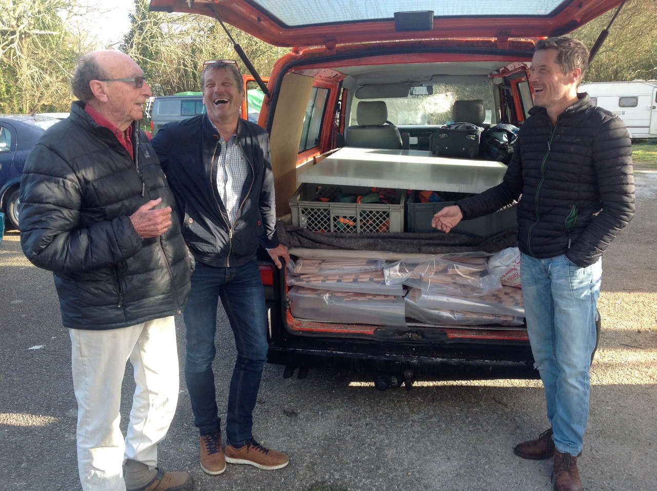 Three men stood at the back of an open van with plywood parts inside