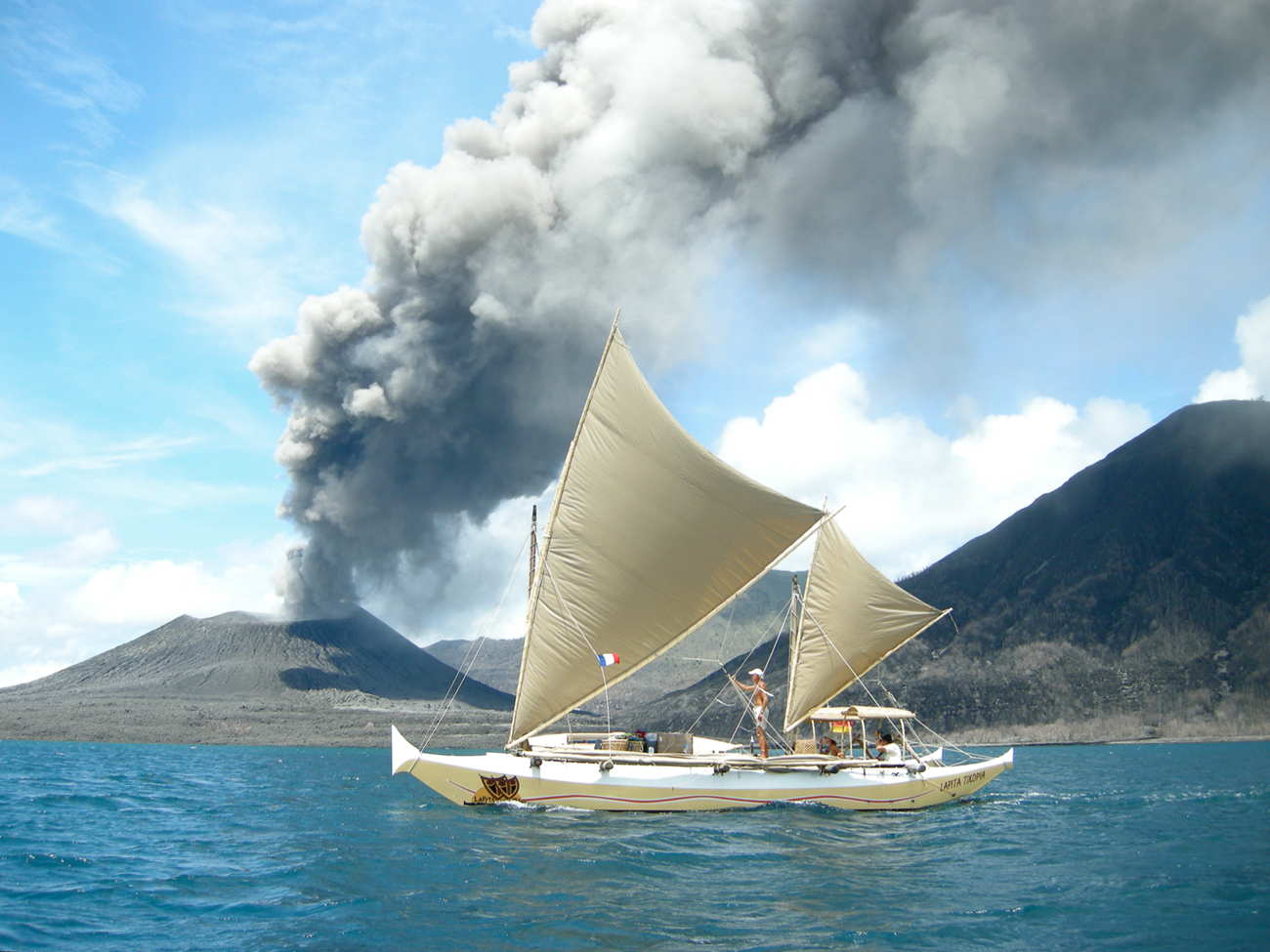 Tama Moana sailing past a smoking volcano
