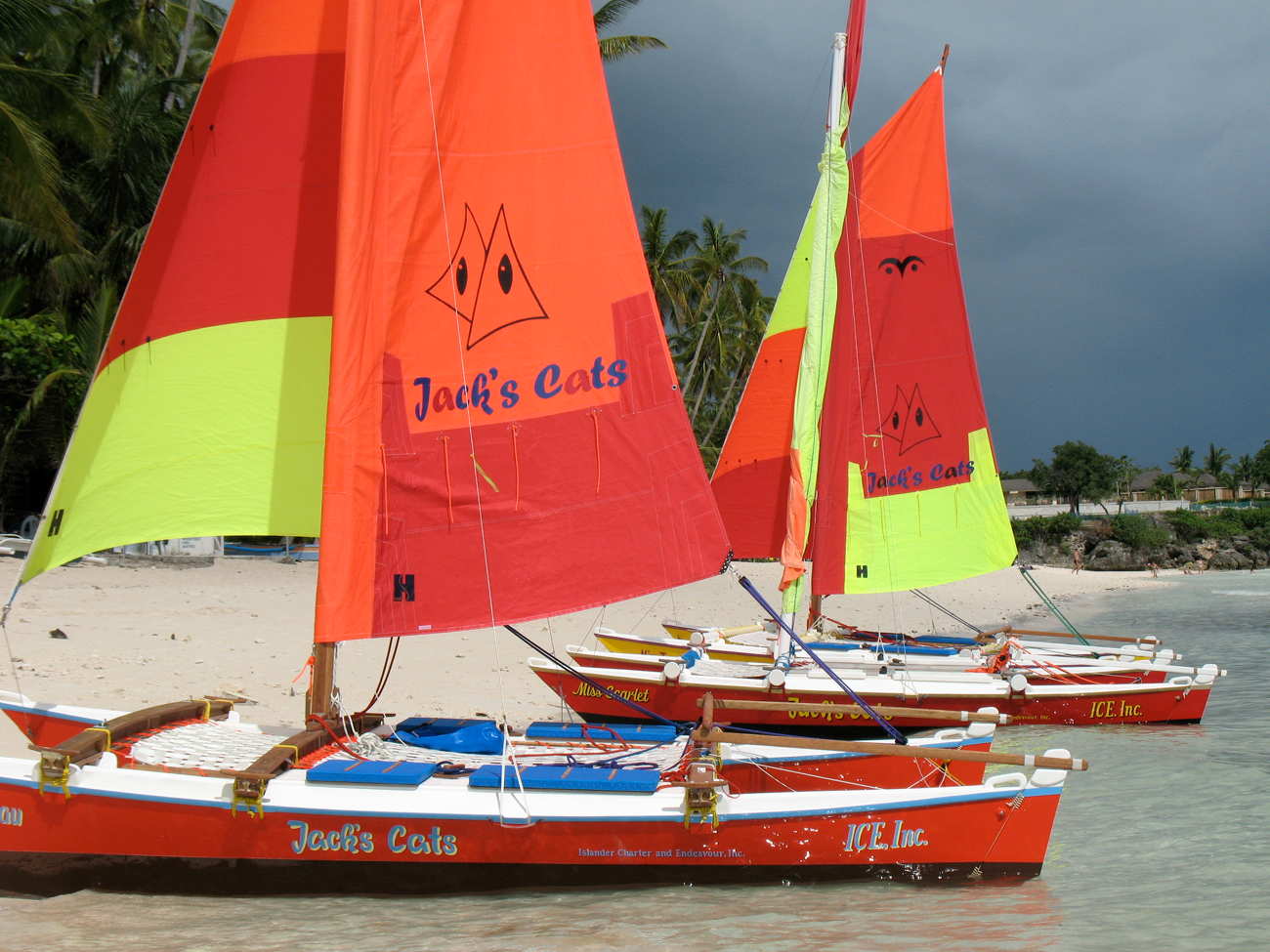 Three Hitia 17s with colourful sails on the beach