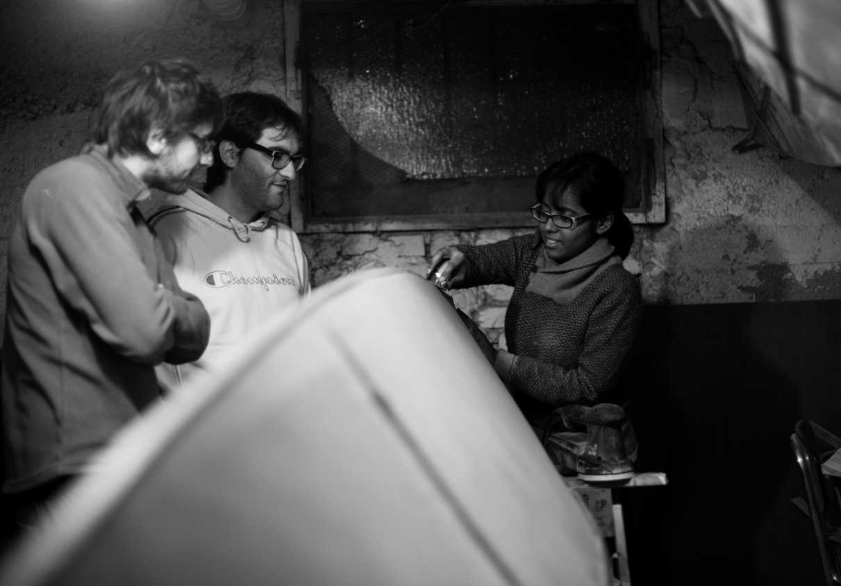 Three people gathered around a hull, black and white photo
