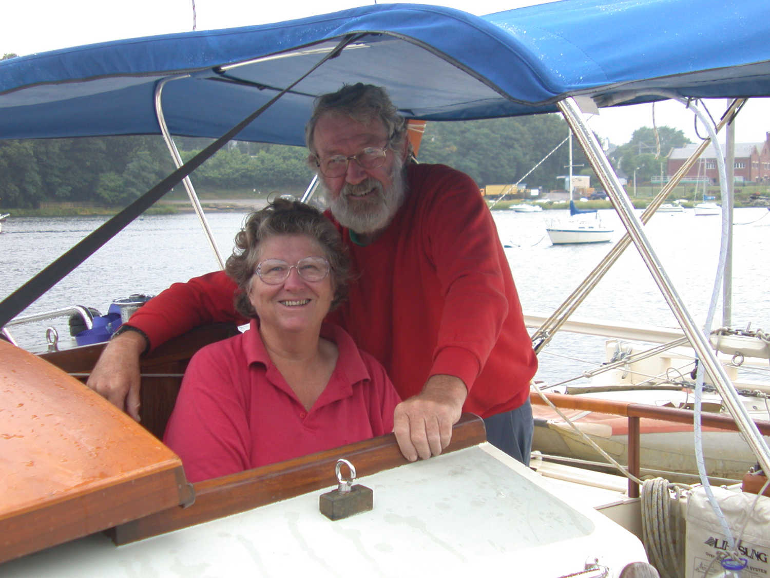 Two people in a boat cockpit, under a canopy