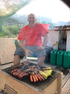 Julius on deck, with food on a wooden firebox barbecue