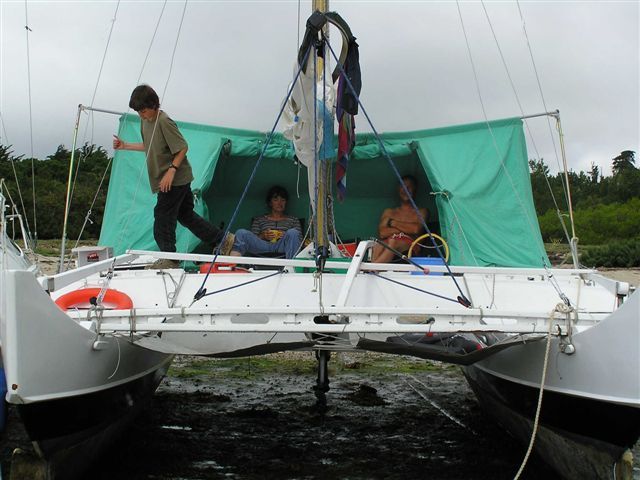 Catamaran with green tent, people aboard