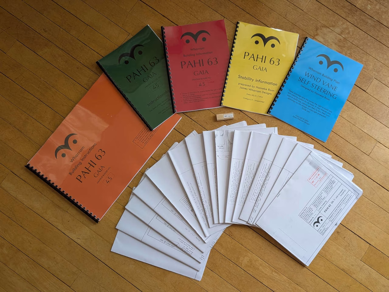 Plan sheets and booklets on a wooden surface