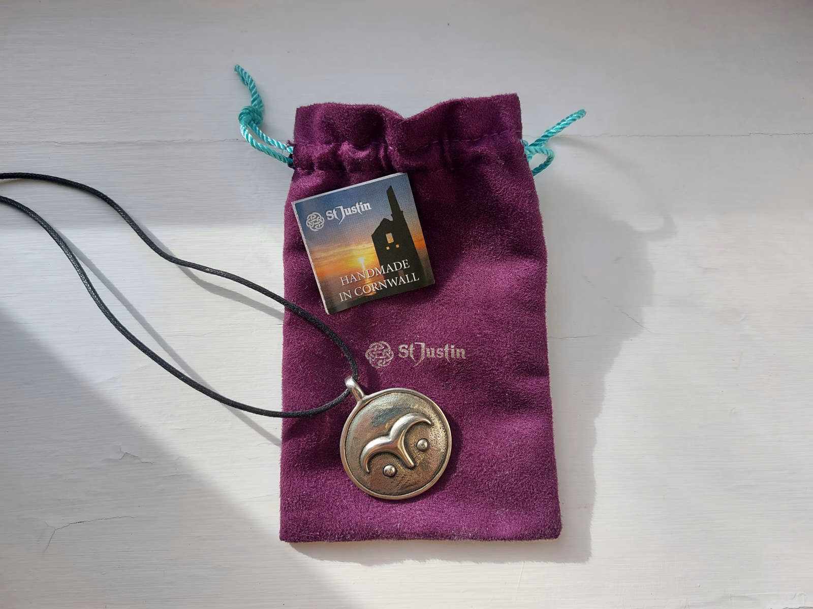A pewter pendant on a purple velvet pouch