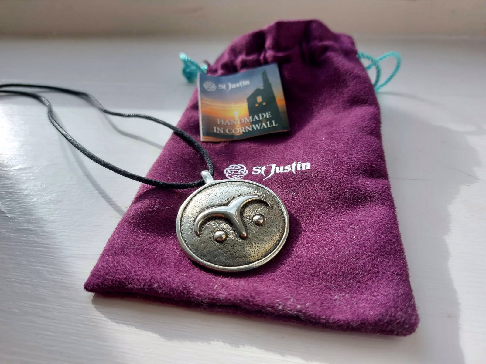A pewter pendant on a purple velvet pouch